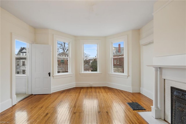 unfurnished living room with light hardwood / wood-style floors and a brick fireplace