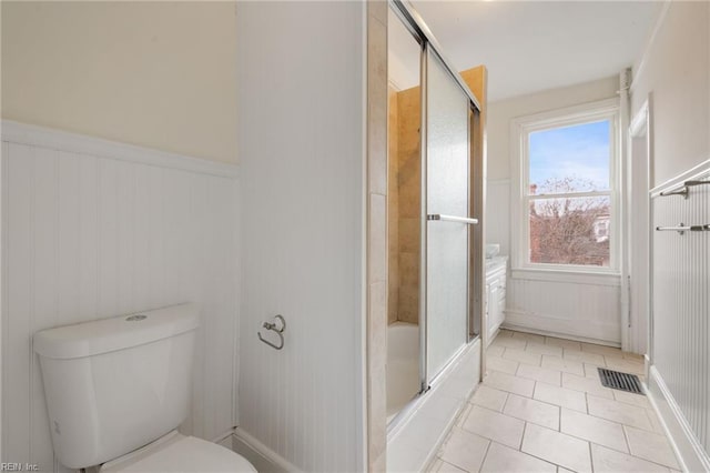 bathroom featuring combined bath / shower with glass door, tile patterned floors, and toilet