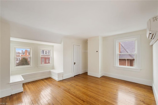 unfurnished room with hardwood / wood-style flooring and a wall mounted AC