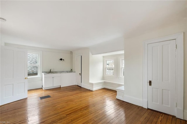 unfurnished living room featuring sink and hardwood / wood-style floors