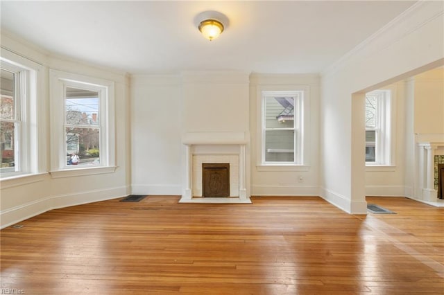 unfurnished living room featuring ornamental molding, a brick fireplace, and light hardwood / wood-style floors