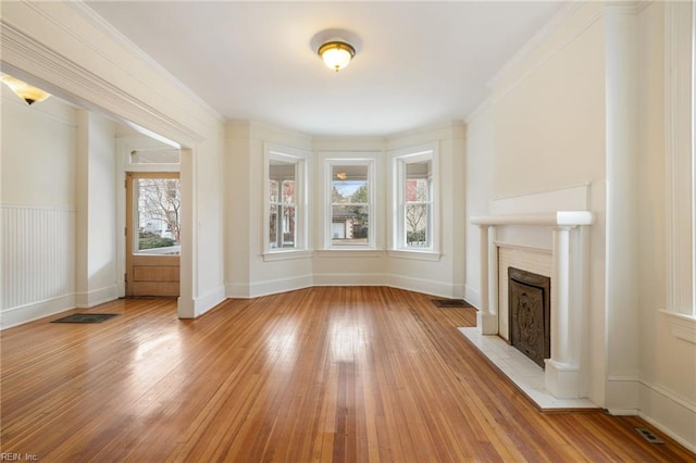 unfurnished living room with ornamental molding and light wood-type flooring