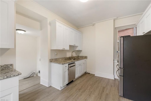 kitchen featuring sink, white cabinets, light stone counters, stainless steel appliances, and light wood-type flooring