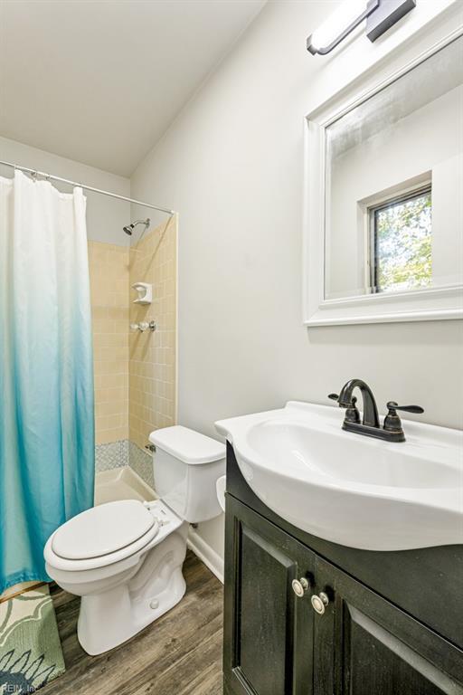 bathroom with hardwood / wood-style flooring, vanity, walk in shower, and toilet