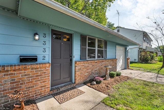 view of exterior entry with a garage and a lawn