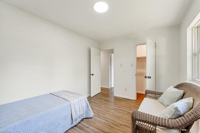 bedroom with a walk in closet and light hardwood / wood-style floors