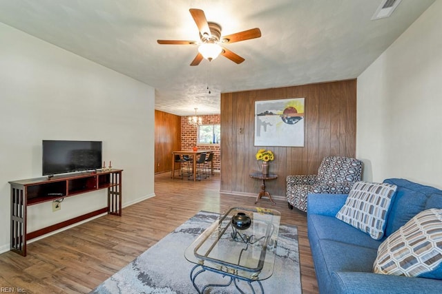 living room with wood-type flooring, wooden walls, and ceiling fan