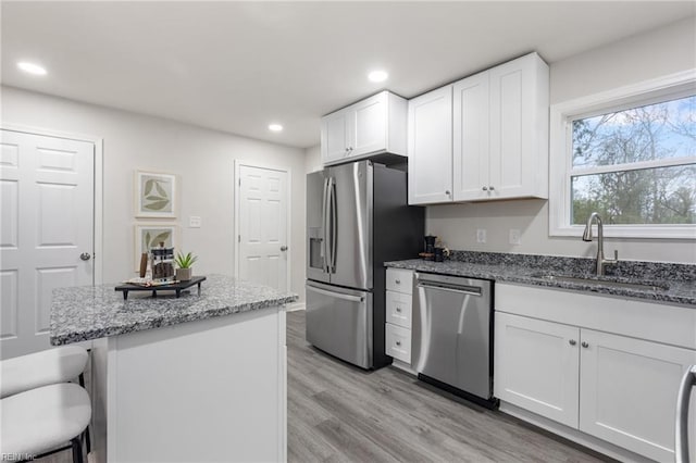 kitchen featuring white cabinetry, sink, a breakfast bar area, dark stone countertops, and stainless steel appliances