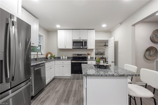 kitchen with stainless steel appliances, stone countertops, a breakfast bar, and white cabinets