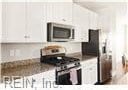 kitchen featuring appliances with stainless steel finishes, dark stone countertops, and white cabinets