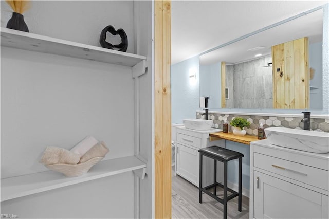 bathroom with vanity, wood-type flooring, decorative backsplash, and a shower