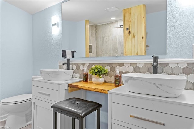 bathroom with vanity, decorative backsplash, toilet, and walk in shower