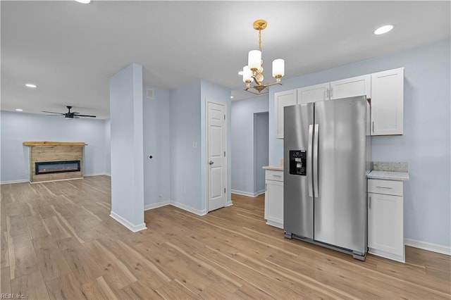 kitchen featuring stainless steel fridge with ice dispenser, light hardwood / wood-style floors, hanging light fixtures, and white cabinets