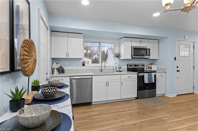 kitchen featuring white cabinetry, sink, stainless steel appliances, and light hardwood / wood-style floors