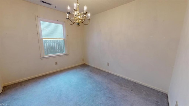 carpeted empty room with a chandelier, visible vents, and baseboards