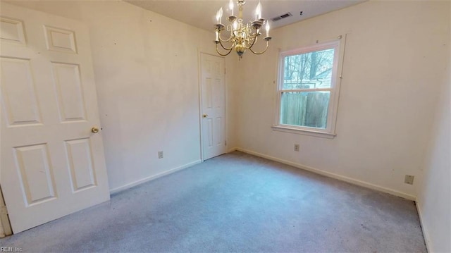 carpeted spare room featuring baseboards, visible vents, and a notable chandelier