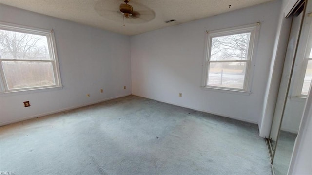 spare room with ceiling fan, visible vents, and light colored carpet