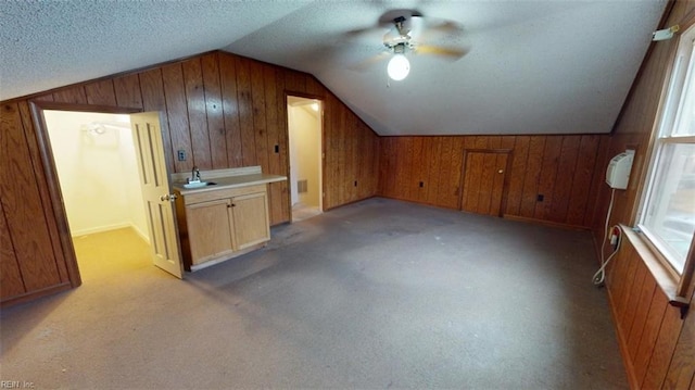 bonus room with light carpet, a textured ceiling, lofted ceiling, and wooden walls