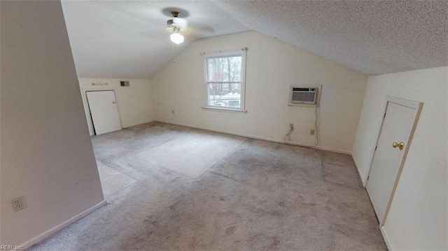 additional living space featuring a textured ceiling, lofted ceiling, carpet floors, visible vents, and a wall mounted air conditioner