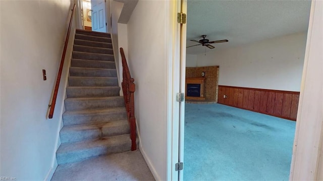 stairway with carpet, a brick fireplace, a wainscoted wall, and wooden walls