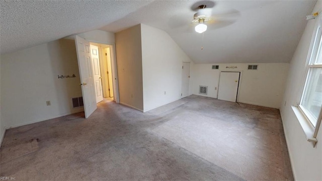 bonus room featuring vaulted ceiling, carpet floors, a textured ceiling, and visible vents