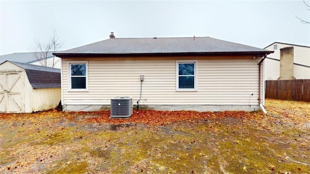 back of house with a storage shed, fence, cooling unit, and an outbuilding