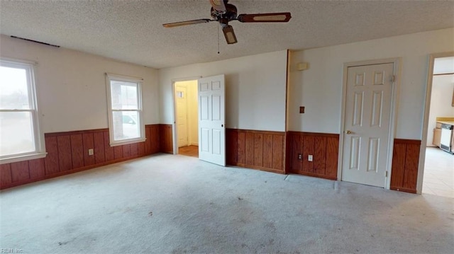 unfurnished bedroom with wooden walls, wainscoting, a textured ceiling, and carpet floors