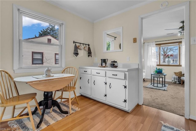 interior space with white cabinetry, ceiling fan, crown molding, and light hardwood / wood-style flooring