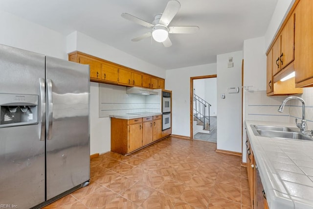 kitchen featuring tasteful backsplash, appliances with stainless steel finishes, tile counters, and sink