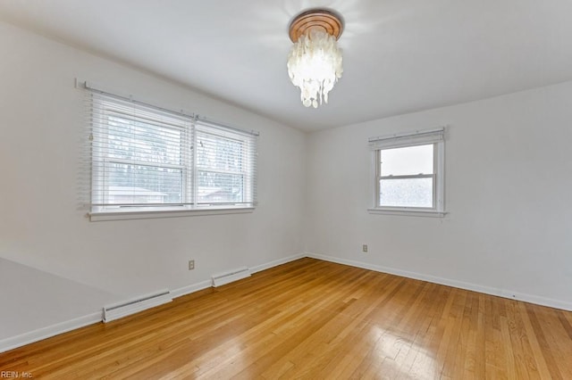 empty room featuring a baseboard heating unit, hardwood / wood-style flooring, and a chandelier