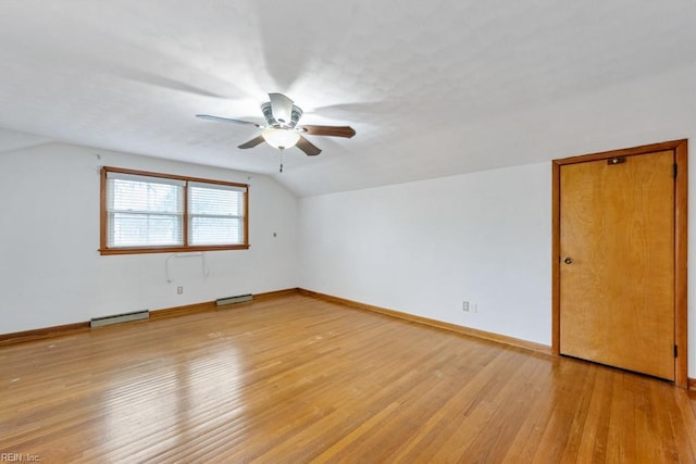 spare room with a baseboard radiator, lofted ceiling, and light wood-type flooring