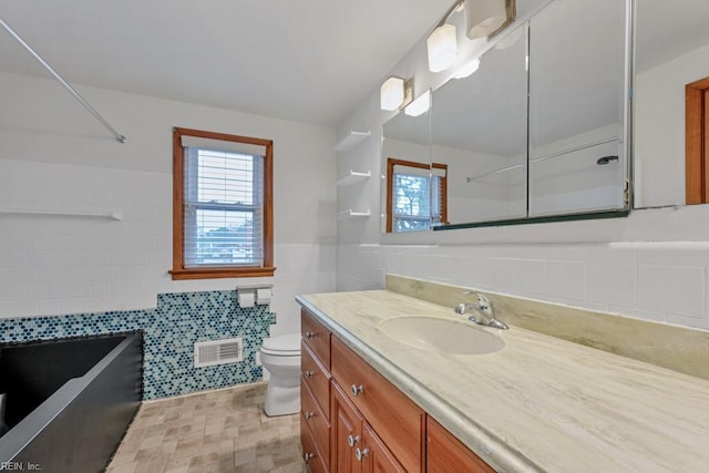 bathroom featuring vanity, tile walls, and toilet