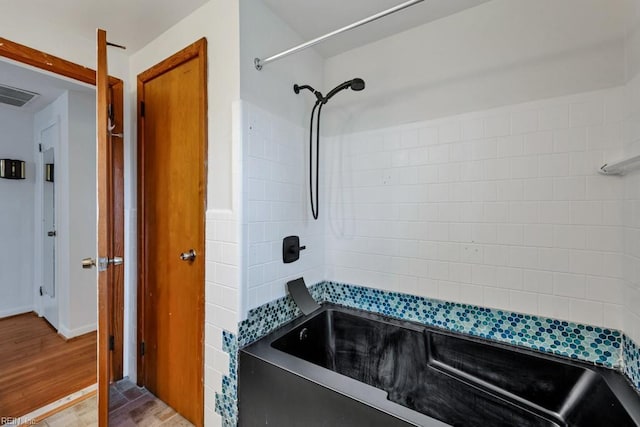 bathroom featuring wood-type flooring and bathing tub / shower combination