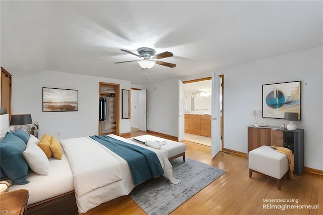 bedroom with ensuite bathroom, a spacious closet, vaulted ceiling, ceiling fan, and light hardwood / wood-style floors