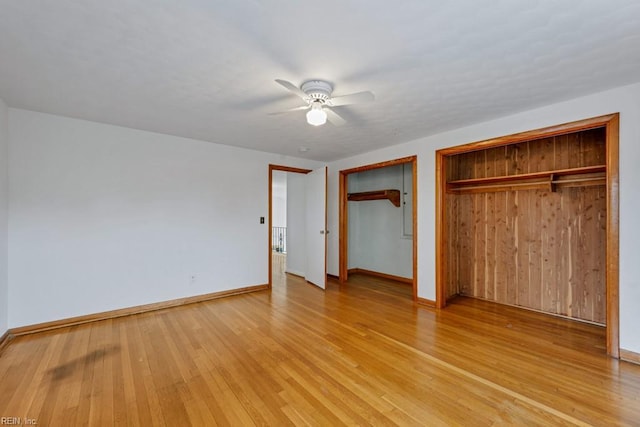 unfurnished bedroom featuring ceiling fan, two closets, and light wood-type flooring