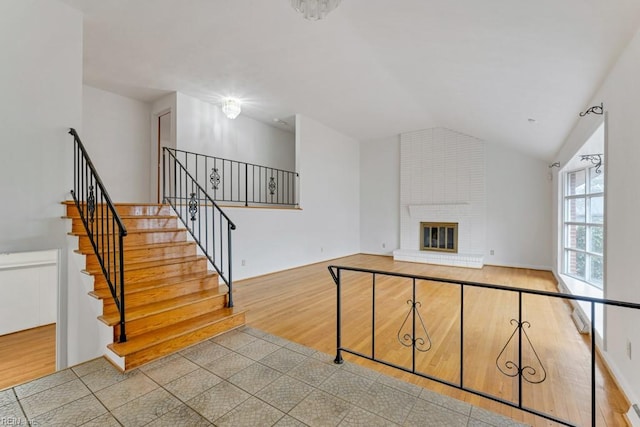 living room with lofted ceiling, a fireplace, and light wood-type flooring