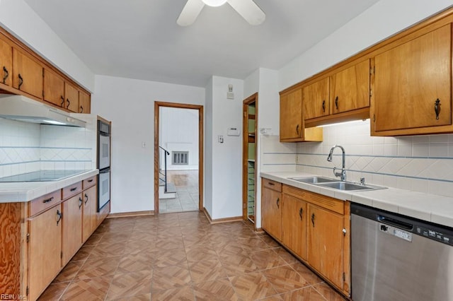 kitchen with sink, backsplash, tile counters, ceiling fan, and stainless steel appliances