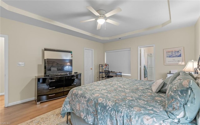 bedroom featuring ceiling fan, wood-type flooring, and a raised ceiling