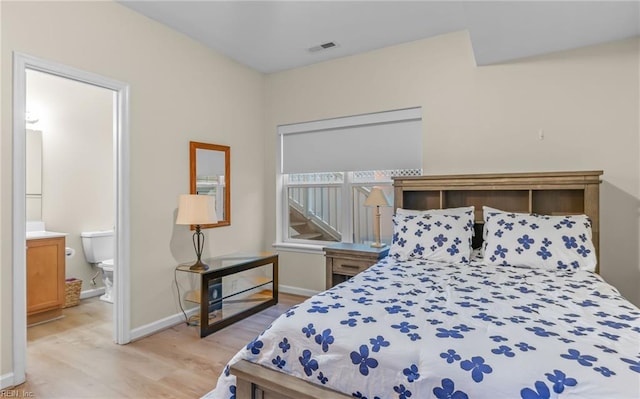 bedroom with connected bathroom and light hardwood / wood-style flooring