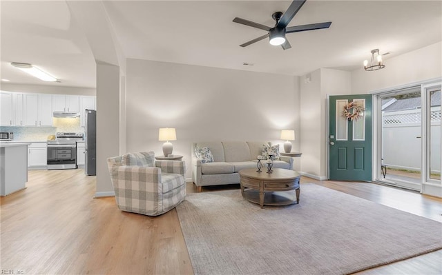 living room with ceiling fan with notable chandelier and light wood-type flooring