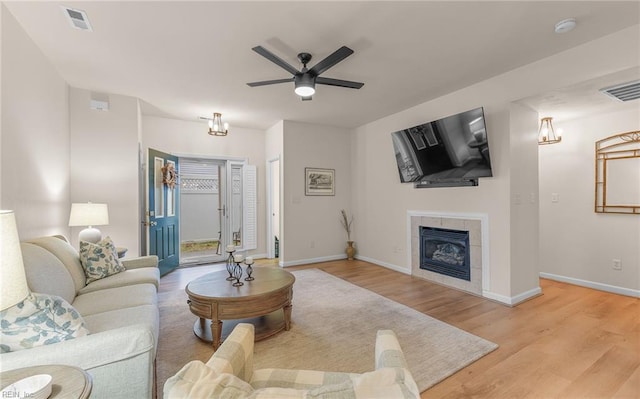 living room featuring ceiling fan, wood-type flooring, and a tile fireplace