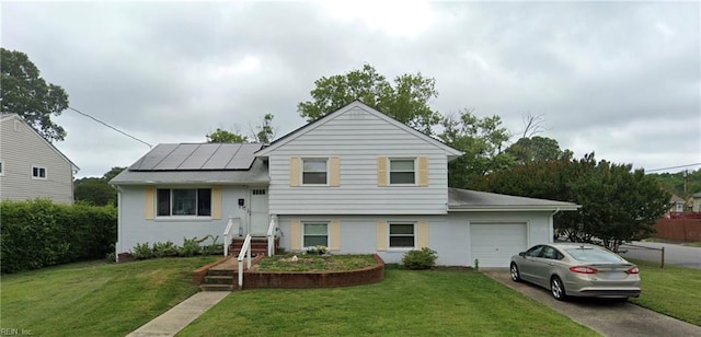 tri-level home with solar panels, concrete driveway, a garage, and a front yard