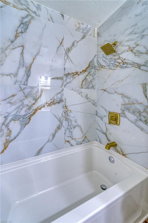 bathroom with a textured ceiling and a washtub