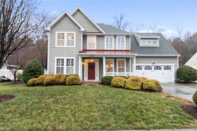 view of front of property featuring a garage, a front lawn, and covered porch