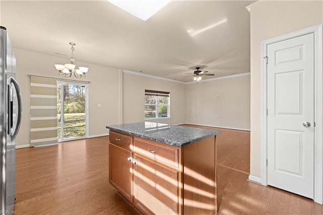 kitchen with crown molding, light hardwood / wood-style flooring, stainless steel refrigerator, hanging light fixtures, and a kitchen island