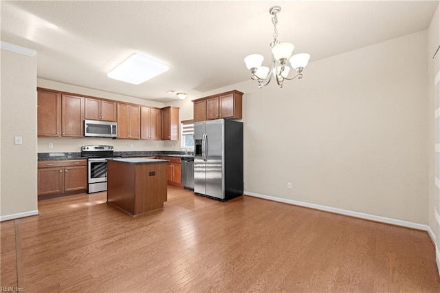 kitchen with appliances with stainless steel finishes, hardwood / wood-style floors, pendant lighting, a chandelier, and a center island