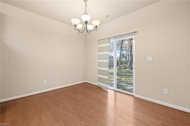 spare room featuring hardwood / wood-style flooring and a notable chandelier