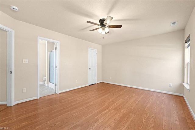 unfurnished bedroom with ceiling fan, ensuite bath, and light wood-type flooring