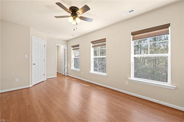 empty room with ceiling fan, plenty of natural light, and light wood-type flooring