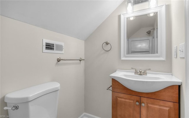 bathroom featuring vanity, toilet, and vaulted ceiling